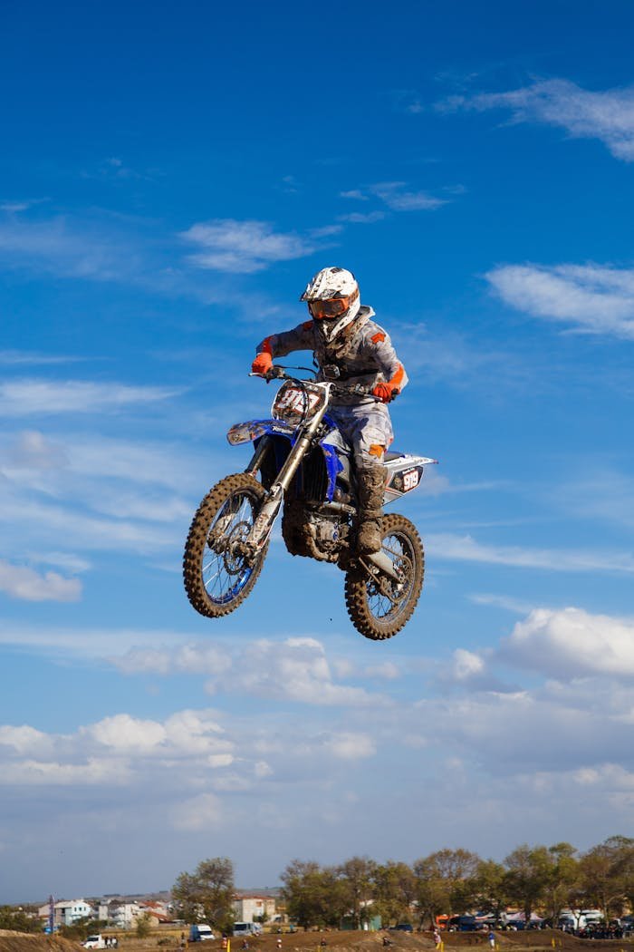 Exciting motocross action shot of a rider performing a jump against a blue sky.
