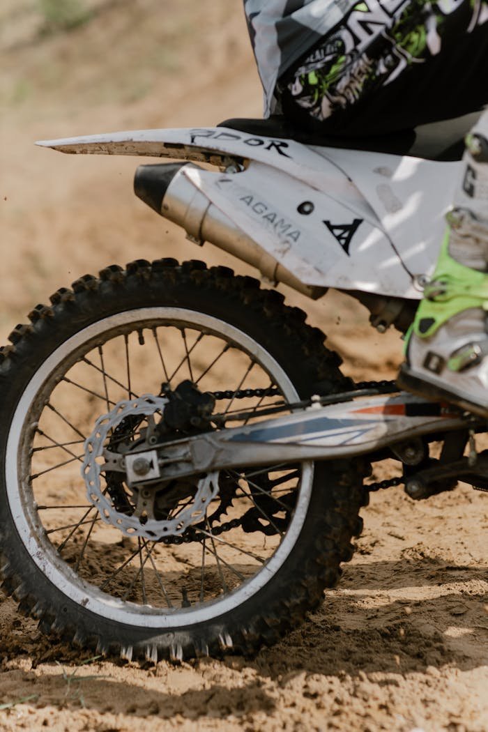 Close-up shot of a dirt bike racing on a muddy track, showcasing speed and action.